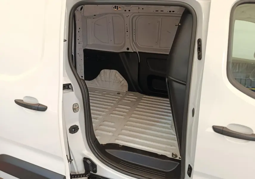 Vue latérale droite du Peugeot Partner blanc 2022 avec porte coulissante ouverte montrant l'espace de chargement vide.