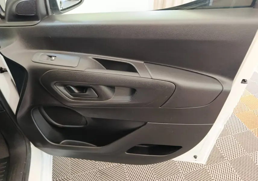 Vue rapprochée de la porte avant gauche noire du Peugeot Partner blanc, avec poignée et haut-parleur intégrés.