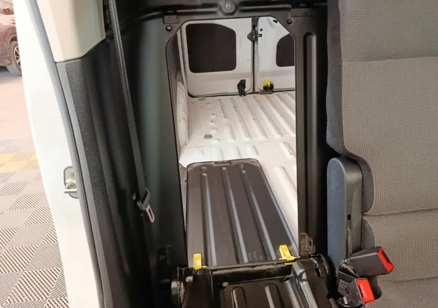 Vue intérieure du compartiment de chargement blanc du Peugeot Partner Taille M, avec cloison pleine et siège rabattable gris.
