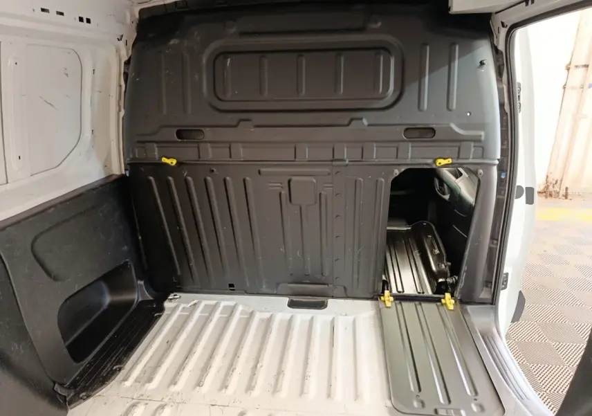 Vue intérieure du compartiment de chargement blanc du Peugeot Partner avec cloison pleine noire et trappe d'accès ouverte côté droit.