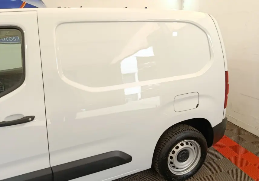 Vue latérale droite d’un utilitaire Peugeot Partner blanc, mettant en valeur la cloison pleine et la roue arrière acier.