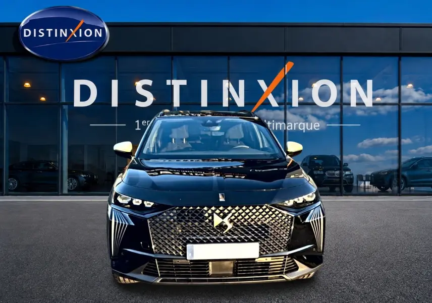 Vue frontale d’un DS7 noir avec calandre distinctive et rétroviseurs blancs devant une vitrine Distinxion.