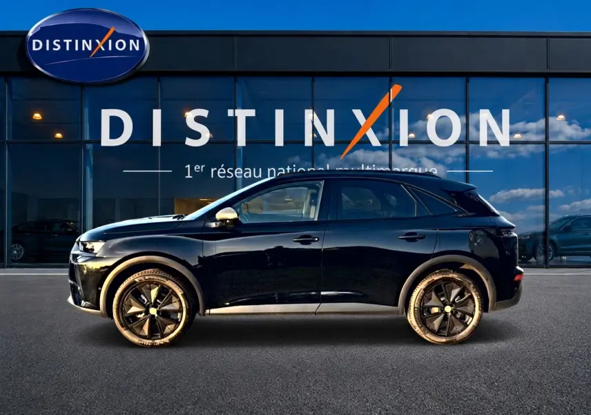 Vue de profil côté gauche d'un DS7 noir 2026 garé devant une vitrine avec logo Distinxion.