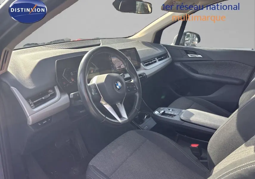 Vue intérieure côté conducteur de la BMW Série 2 Active Tourer 218d 2023 avec tableau de bord moderne et sièges tissu gris.
