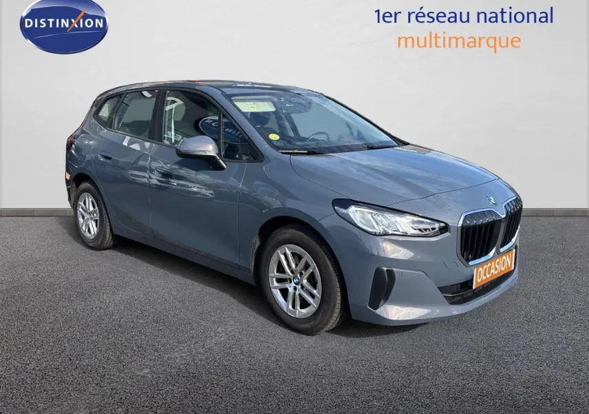 BMW Série 2 Active Tourer 218d gris Sparkling Copper, vue 3/4 avant droit sur fond neutre showroom.