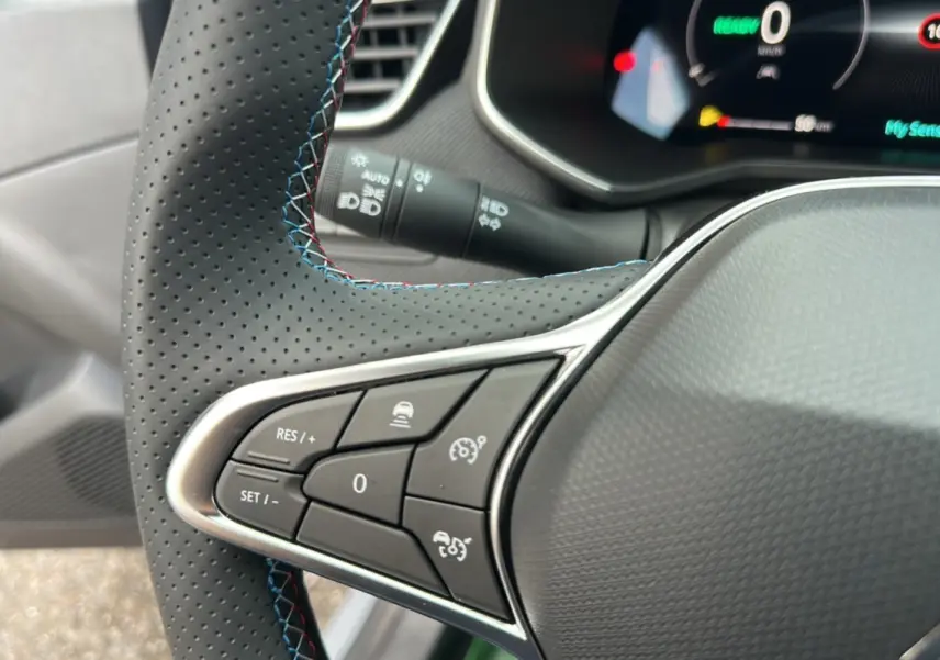 Gros plan sur le volant cuir perforé avec surpiqûres bleues de la Renault Clio V E-Tech 145 Esprit Alpine Bose.