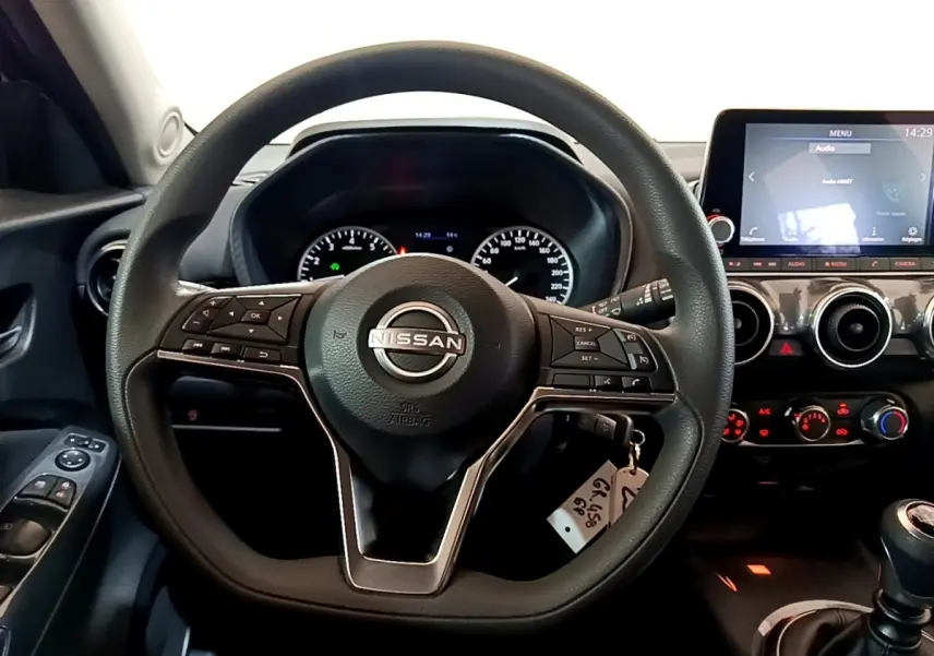 Vue intérieure centrée sur le volant multifonctions noir d’un Nissan Juke 2023 avec tableau de bord et écran tactile.