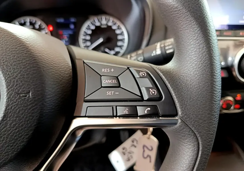 Gros plan sur le côté droit du volant noir du Nissan Juke 2023 avec commandes du régulateur de vitesse et téléphone.