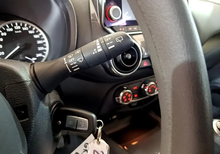 Gros plan intérieur côté gauche du volant noir du Nissan Juke 2023, avec commandes d'essuie-glace et tableau de bord.