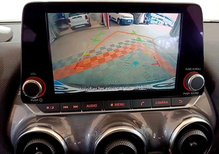 Écran tactile central du Nissan Juke noir 2023 montrant la caméra de recul avec lignes de guidage colorées.