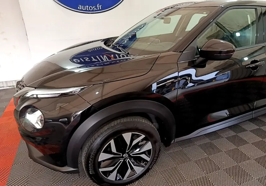 Vue 3/4 avant gauche du Nissan Juke noir 2023 avec jantes alliage bicolores et phares LED ellipsoïdaux.