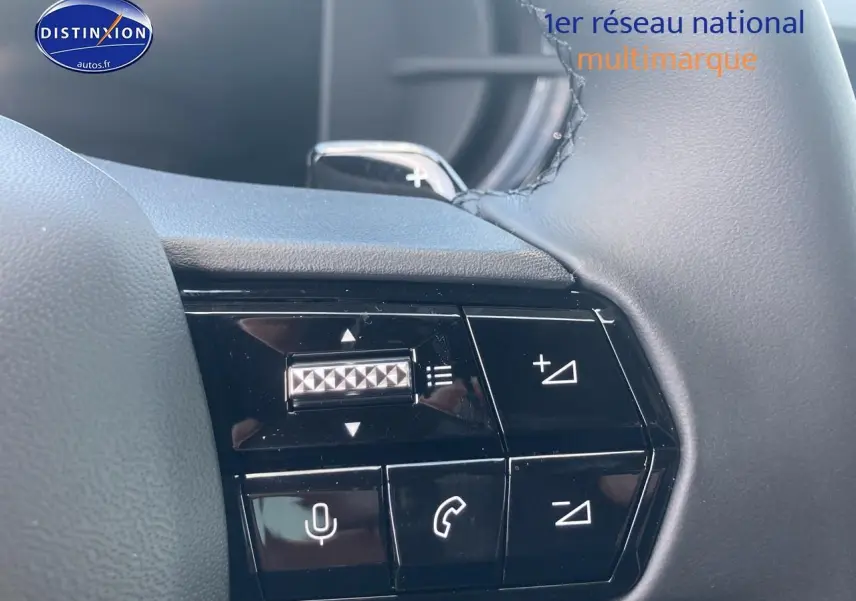 Gros plan sur les commandes au volant côté gauche de l'Alfa Romeo Junior gris, avec boutons de volume et téléphone.