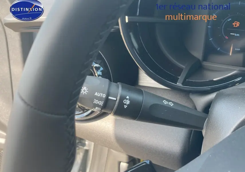 Gros plan sur la manette de clignotants et phares à gauche du volant dans l’habitacle gris d’une Alfa Romeo Junior 1.2 hybride.