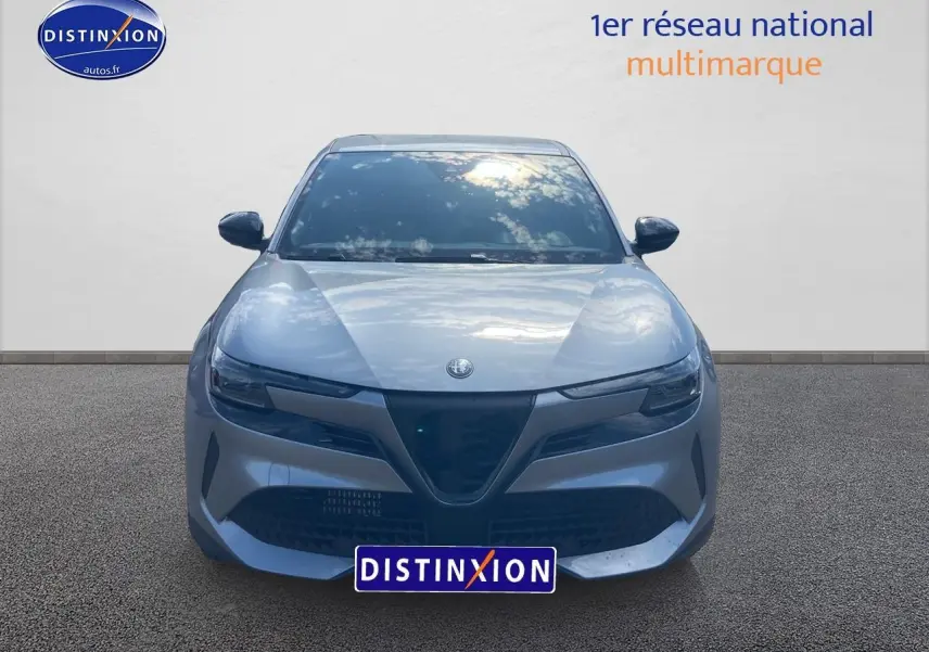 Vue avant d'une Alfa Romeo Junior 1.2 hybride gris métallisé avec calandre caractéristique et phares LED fins.