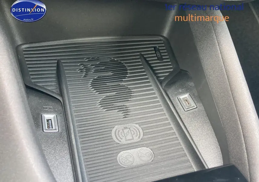 Gros plan sur le chargeur à induction avec logo serpent Alfa Romeo, entouré de ports USB dans l'habitacle gris.