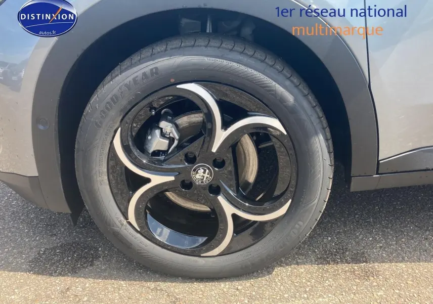 Gros plan sur la jante en alliage noire et argentée de l'Alfa Romeo Junior gris, côté arrière droit.