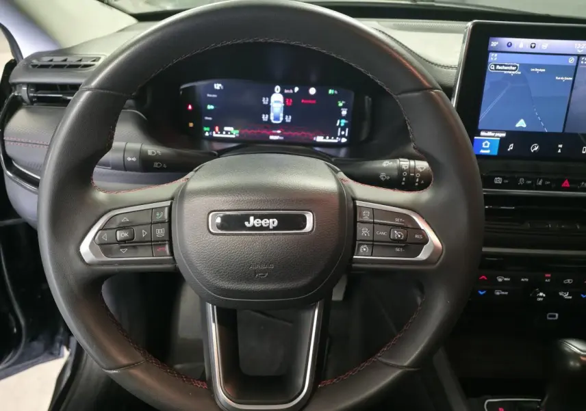 Vue rapprochée du volant noir avec surpiqûres rouges du Jeep Compass 2022, affichage numérique et écran tactile visible.
