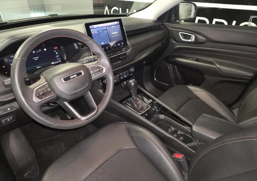 Vue intérieure côté conducteur du Jeep Compass noir 2022, avec tableau de bord numérique et console centrale moderne.