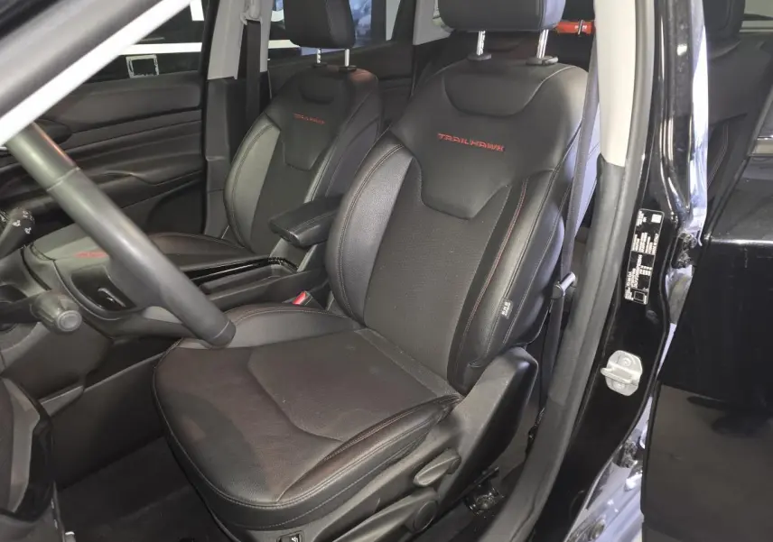 Vue intérieure côté conducteur du Jeep Compass Trailhawk 2022 noir, sièges en cuir noir avec logo Trailhawk rouge brodé.