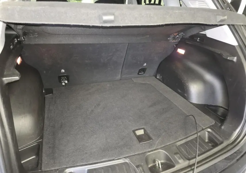 Coffre ouvert vu de l'arrière du Jeep Compass Trailhawk noir, montrant l'espace de chargement et l'éclairage intérieur.