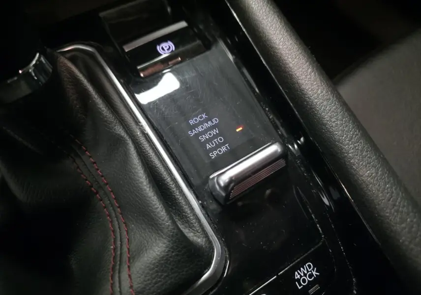 Gros plan sur la console centrale noire du Jeep Compass Trailhawk avec sélecteur modes tout-terrain et frein électrique.