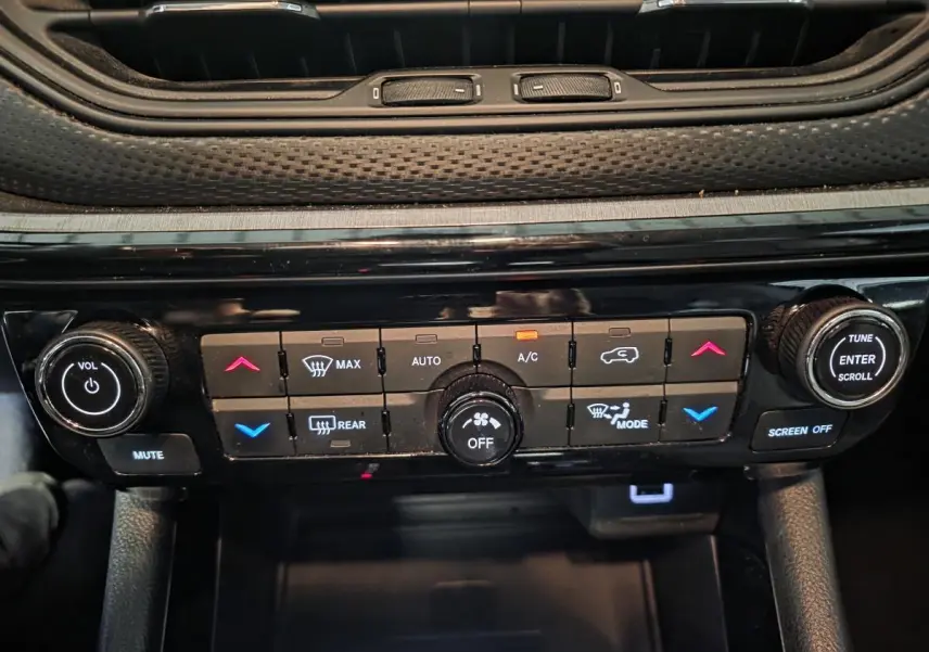 Vue rapprochée du panneau de commande de climatisation et audio noir du Jeep Compass Trailhawk 2022.