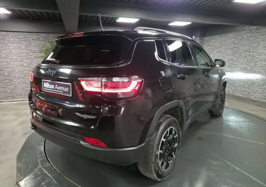 Vue 3/4 arrière droite d'un Jeep Compass noir avec feux arrière allumés et jantes alliage noires en intérieur.