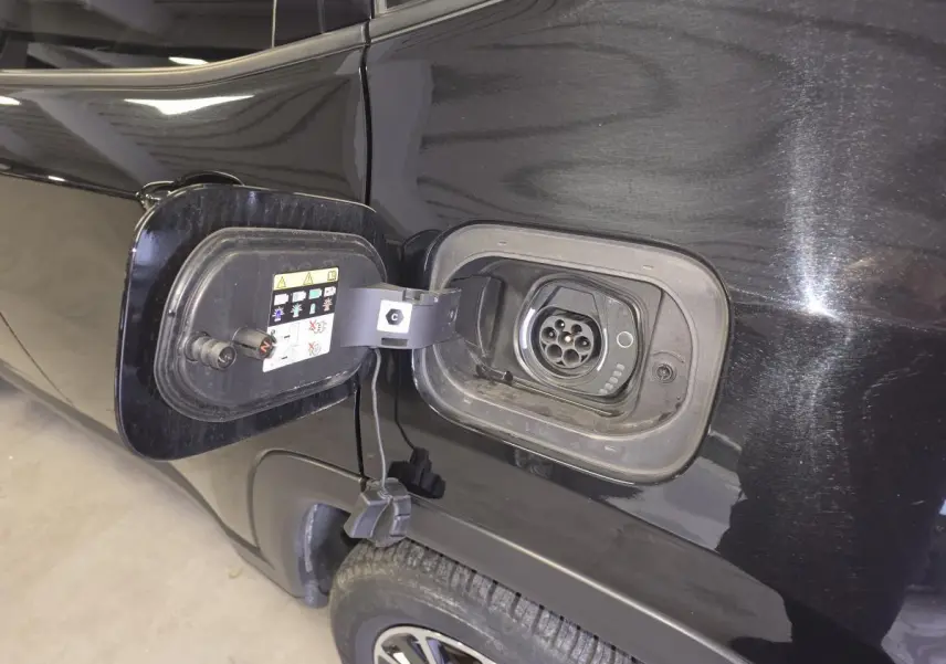 Gros plan sur la trappe de recharge côté gauche d’un Jeep Compass Trailhawk noir avec prise Type 2 visible.