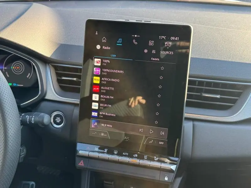 Vue intérieure centrée sur l'écran tactile vertical du tableau de bord du Renault Captur rouge 2025.