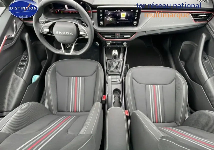 Vue intérieure frontale du Skoda Kamiq noir, mettant en valeur les sièges sport avec bandes rouges et grises et le tableau de bord moderne.