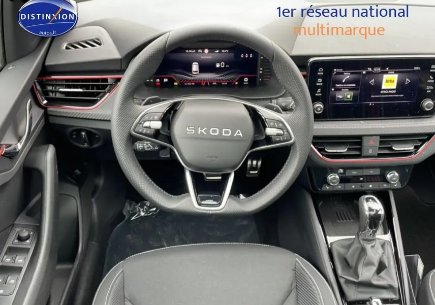 Vue intérieure centrée sur le volant SKODA noir et le tableau de bord avec écran tactile et détails rouges.