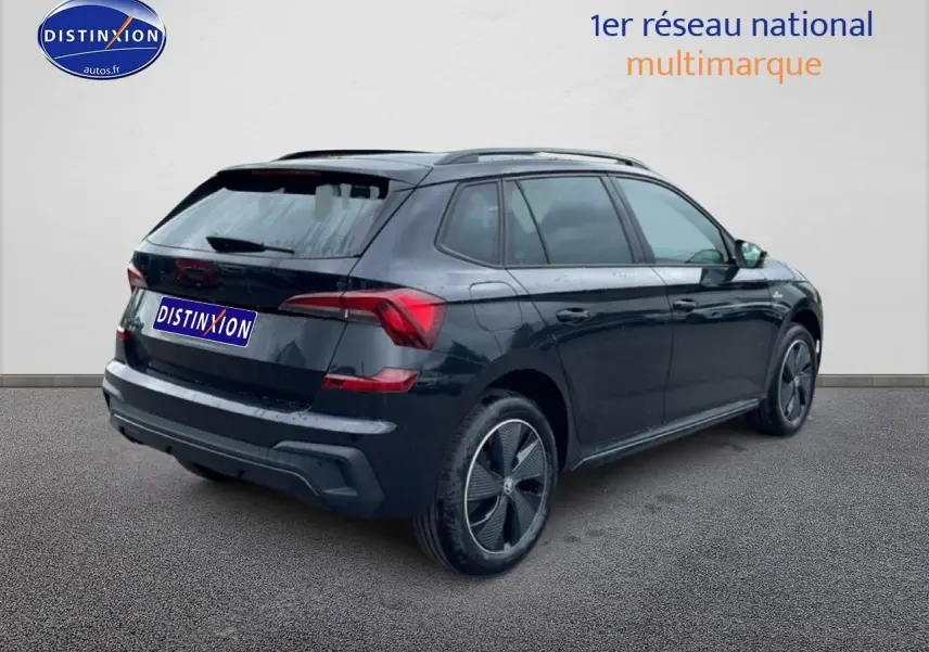 Vue 3/4 arrière droite d'un Skoda Kamiq noir avec jantes alu et barres de toit, sur fond neutre.