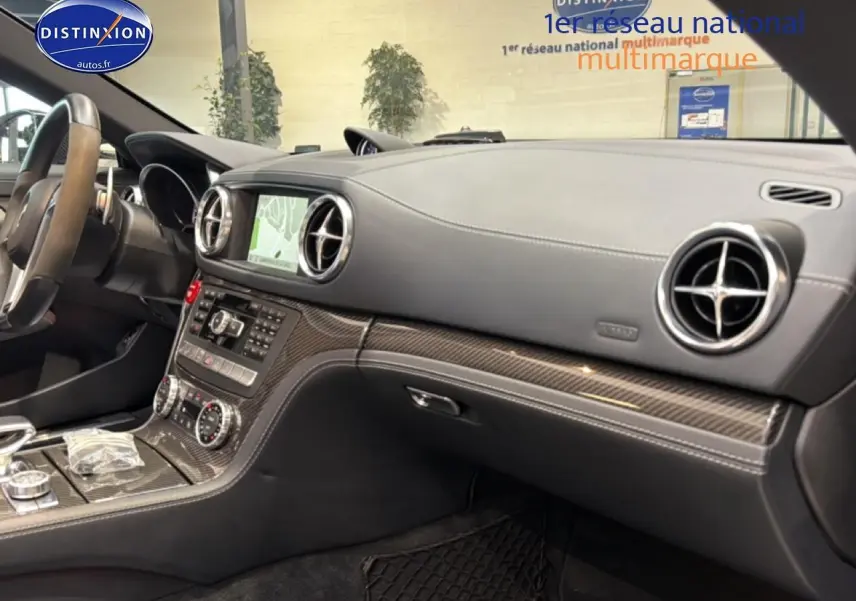 Vue intérieure côté passager du tableau de bord en cuir noir avec inserts carbone et écran GPS de la Mercedes Classe SL 63 AMG.