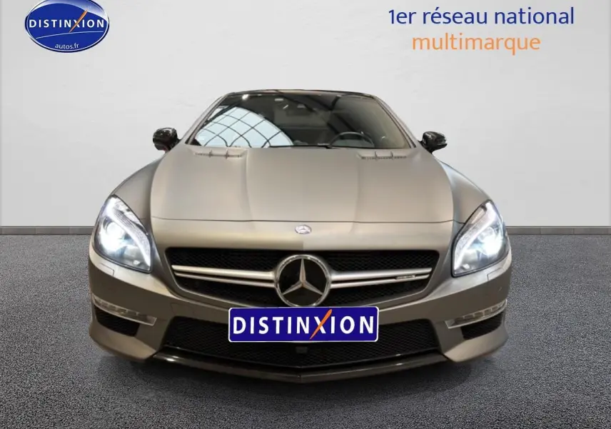 Vue frontale d'une Mercedes Classe SL 63 AMG gris métallisé avec phares allumés et calandre chromée.