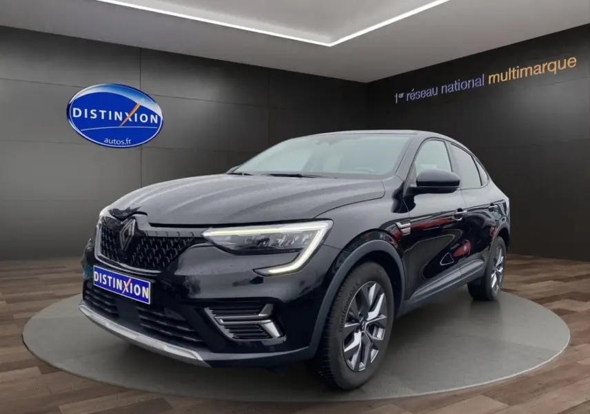 Renault Arkana noir en 3/4 avant droit, avec phares LED allumés et jantes alliage visibles en showroom.