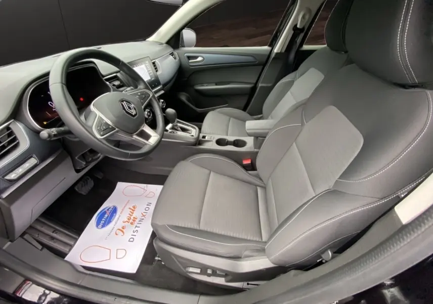 Vue intérieure côté conducteur de la Renault Arkana noire 2024, montrant sièges en tissu et volant multifonctions.