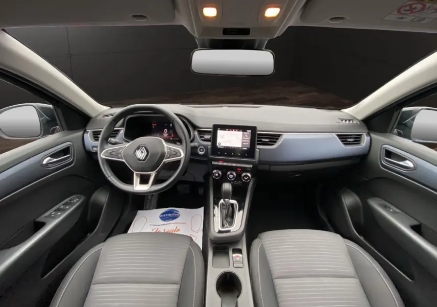 Vue intérieure avant du Renault Arkana 2024 noir, avec tableau de bord moderne et écran tactile central.