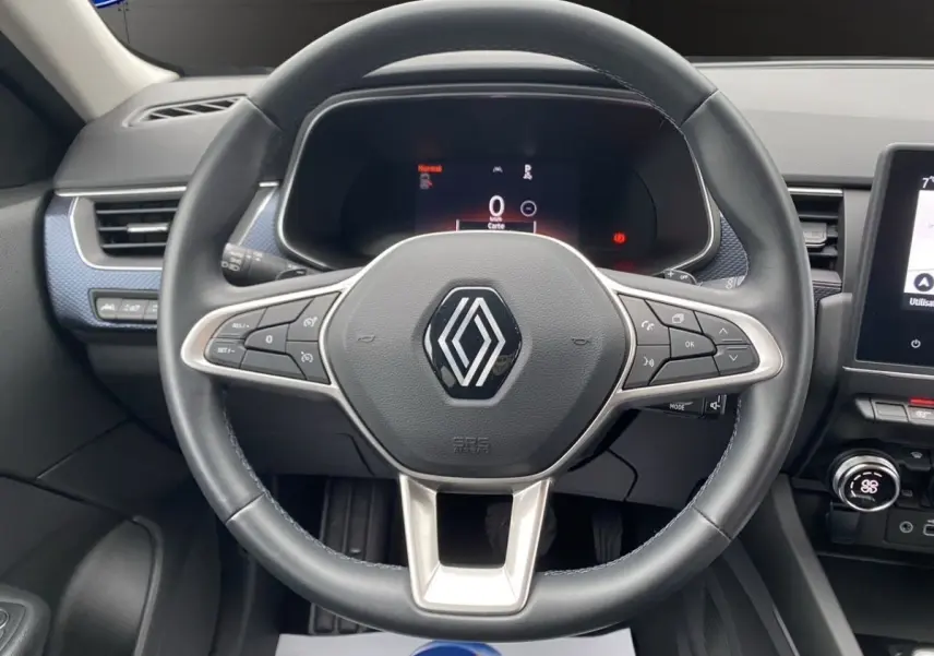 Vue centrée sur le volant cuir noir de la Renault Arkana 2024 avec tableau de bord numérique et écran tactile latéral.