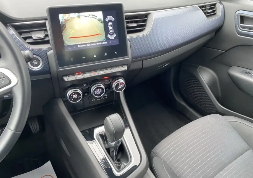Vue intérieure côté passager du tableau de bord et console centrale de la Renault Arkana noire avec écran tactile et levier de boîte auto.