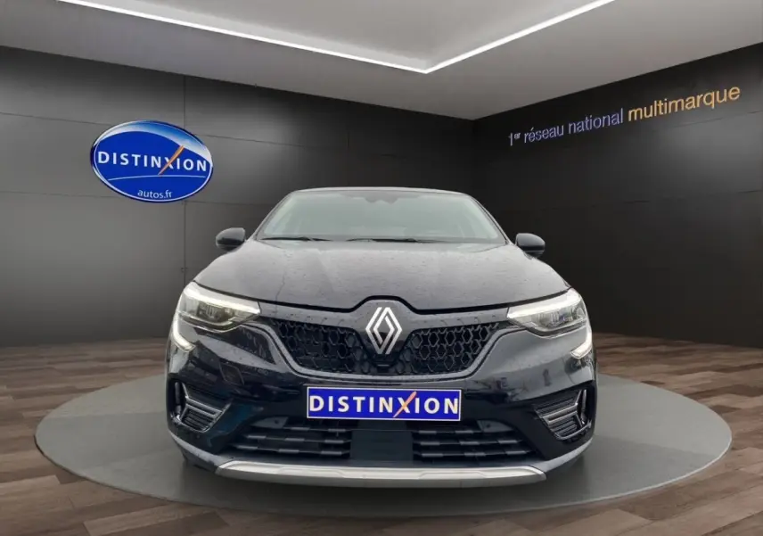 Vue avant d’une Renault Arkana noire 2024 avec calandre noire et phares LED allumés en showroom.