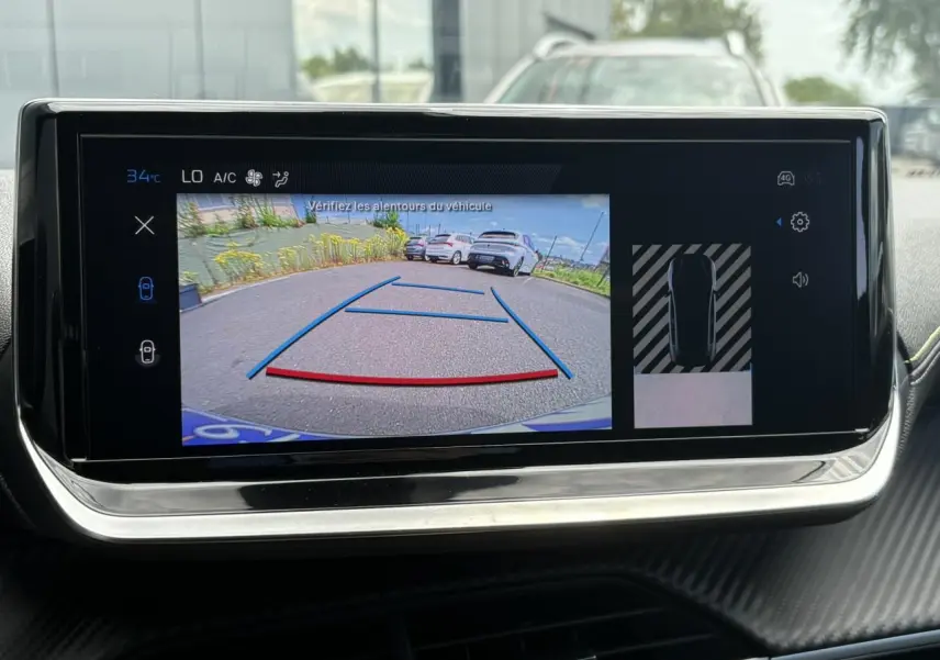 Écran tactile intérieur montrant la caméra de recul avec vue arrière et lignes de guidage sur Peugeot 208 Bleu Vertigo.