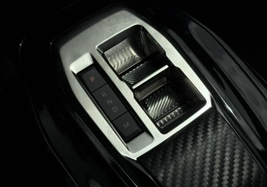 Gros plan sur la console centrale avec sélecteur de boîte automatique et finition carbone du Peugeot 208 Hybrid 110 GT.