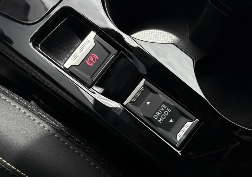 Gros plan sur la console centrale noire brillante de la Peugeot 208 Hybrid 110 e-DSC6 GT avec bouton frein électrique et sélecteur Drive Mode.