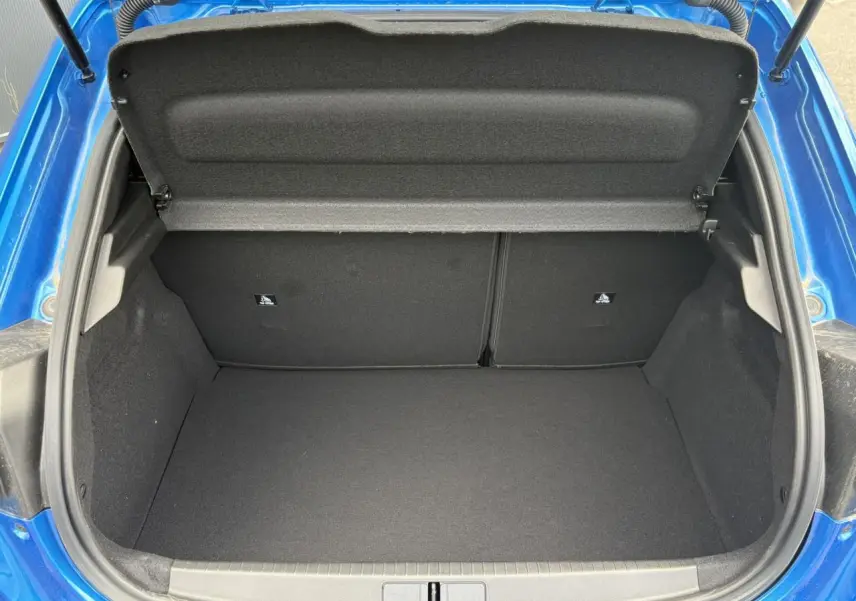 Coffre ouvert vu de l'arrière d'une Peugeot 208 Hybrid 110 e-DSC6 GT bleu Vertigo, montrant l'espace de chargement vide.