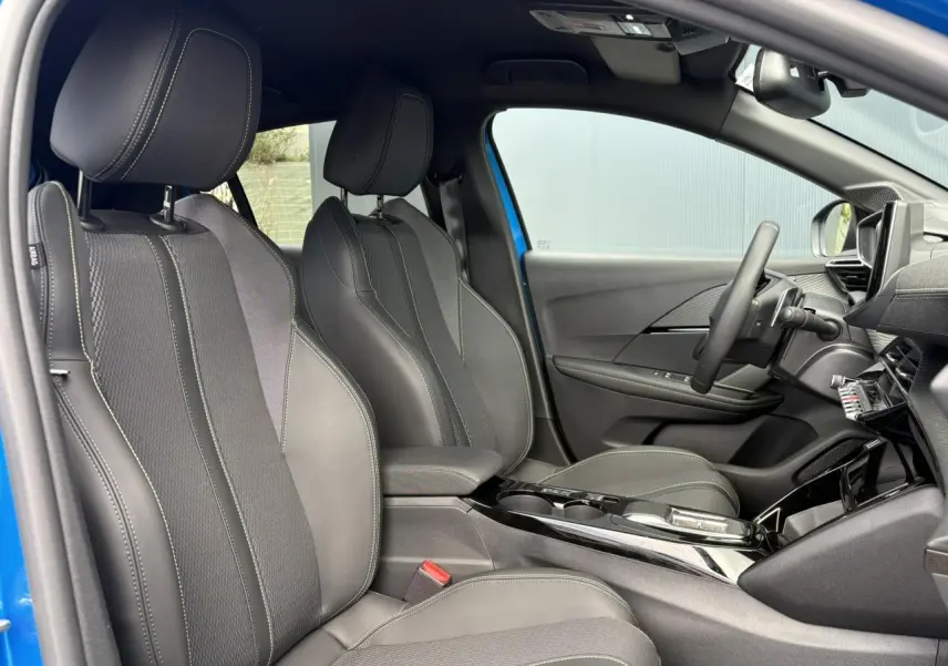 Intérieur avant droit de la Peugeot 208 Hybrid 110 GT bleu Vertigo, sièges tissu et TEP avec surpiqûres vertes.