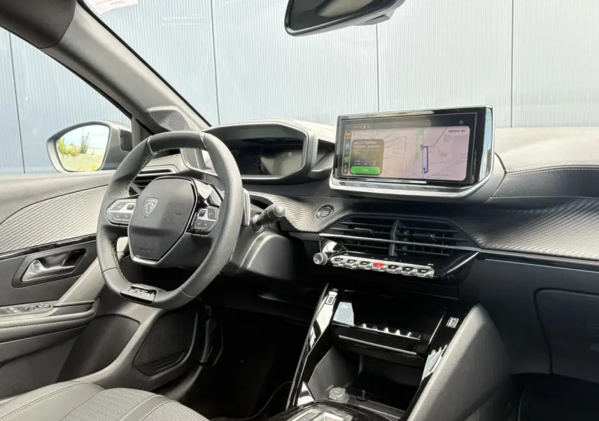Vue intérieure côté conducteur du Peugeot 208 Hybrid 110 GT avec tableau de bord numérique et écran tactile central.