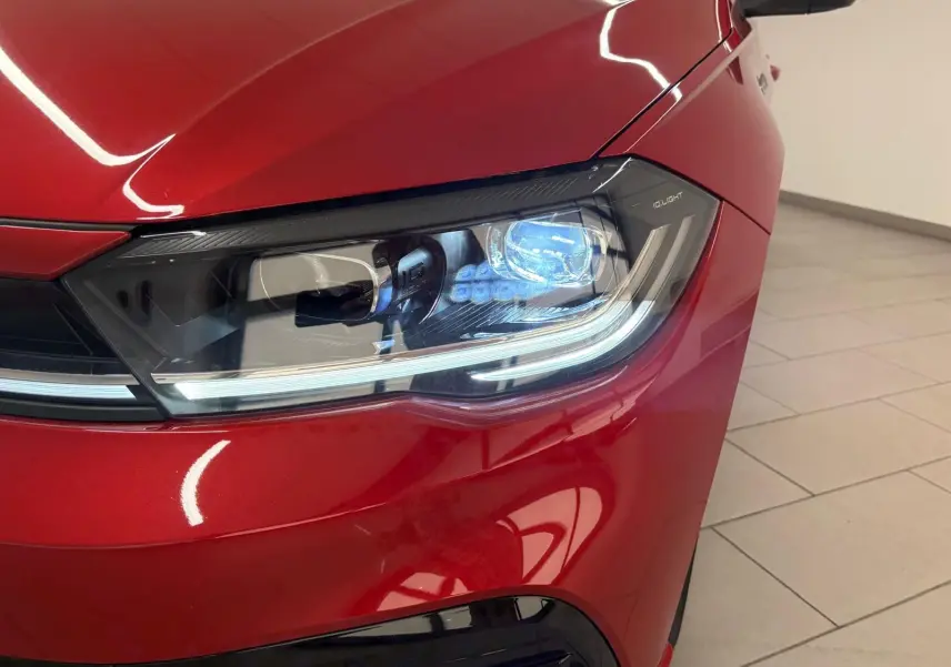 Gros plan sur le phare avant droit d'une Volkswagen Polo Rouge Roi 2025 avec peinture métallisée et signature lumineuse LED.