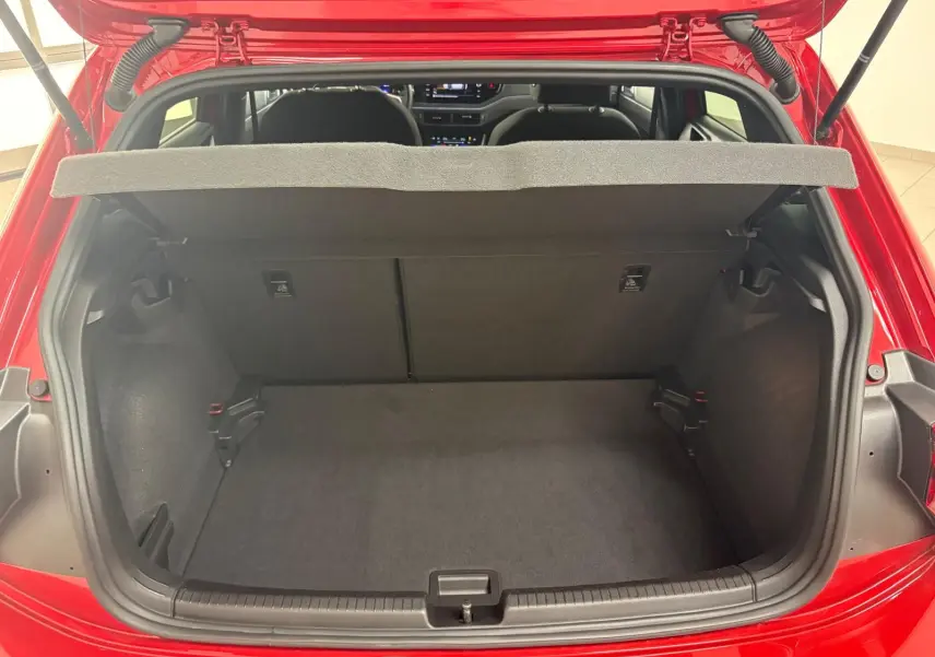 Vue arrière du coffre ouvert d'une Volkswagen Polo Rouge Roi 2025, montrant l'espace de rangement vide et la tablette cache-bagages.