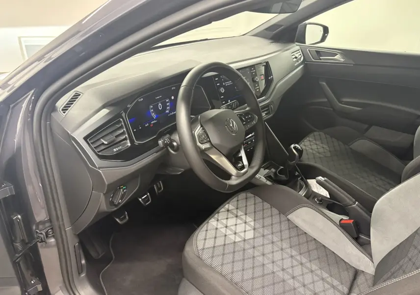 Vue intérieure côté conducteur de la Volkswagen Polo 1.0 TSI R-Line 2025, montrant le volant, tableau de bord digital et sièges tissu gris.