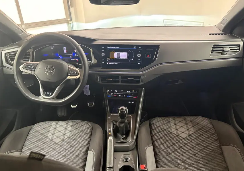 Vue intérieure avant du tableau de bord et volant Volkswagen Polo 2025 avec boîte manuelle et sièges tissu à motif géométrique.